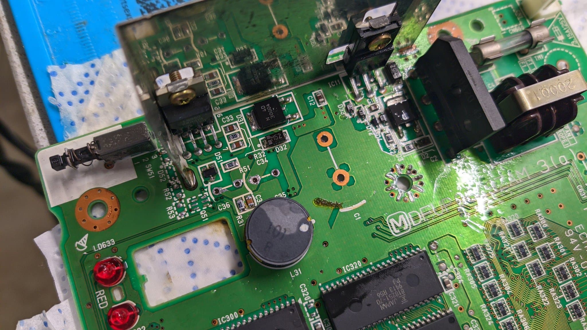 Panasonic FZ-1 motherboard mid-recap; through-hole solder joints with oxidation, capacitors, and IC chips visible during restoration work.