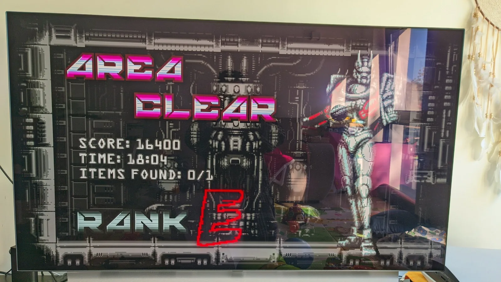 Vengeful Guardian: Moonrider 'AREA CLEAR' results screen on an LG C1 OLED TV, reading SCORE 16400, TIME 18:04, ITEMS FOUND 0/1 and RANK E.