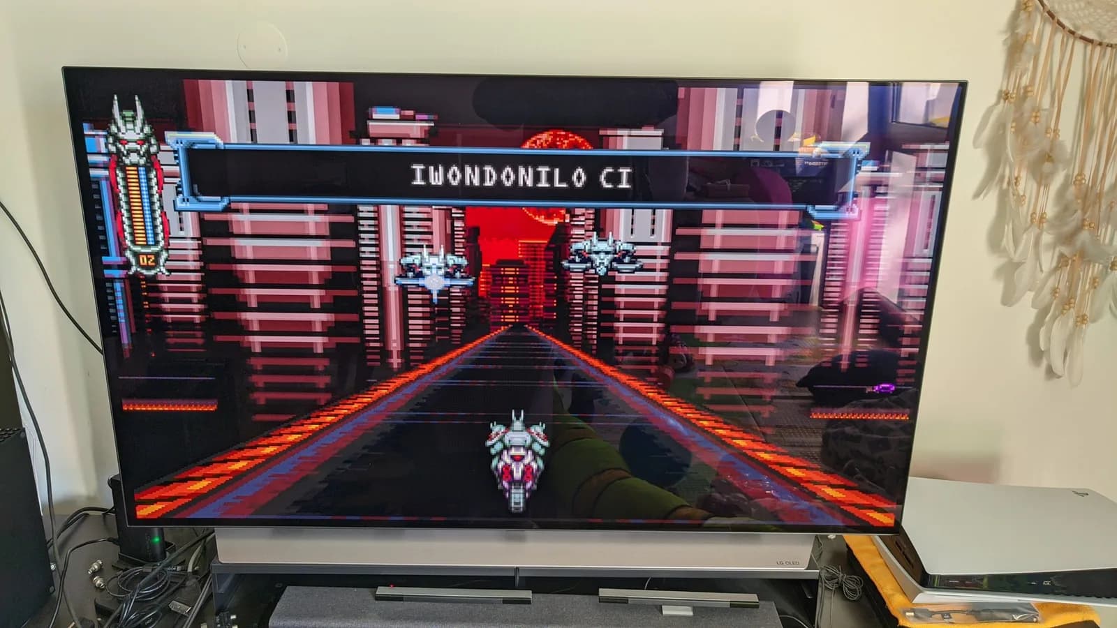 Vengeful Guardian: Moonrider on a large LG C1 OLED TV, the player riding a motorcycle down a neon-lit road into a brown and orange pixel-art cityscape, a dialogue box across the top.
