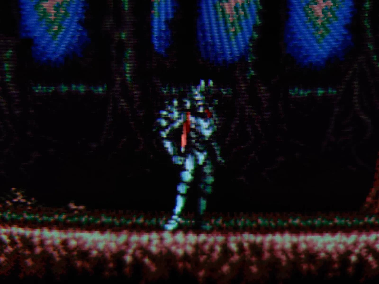 Vengeful Guardian: Moonrider on the Sony BVM-D14H1E, the armored Moonrider centered in a dark forest stage with blue glowing patches above and brownish ground below, CRT scanlines visible.