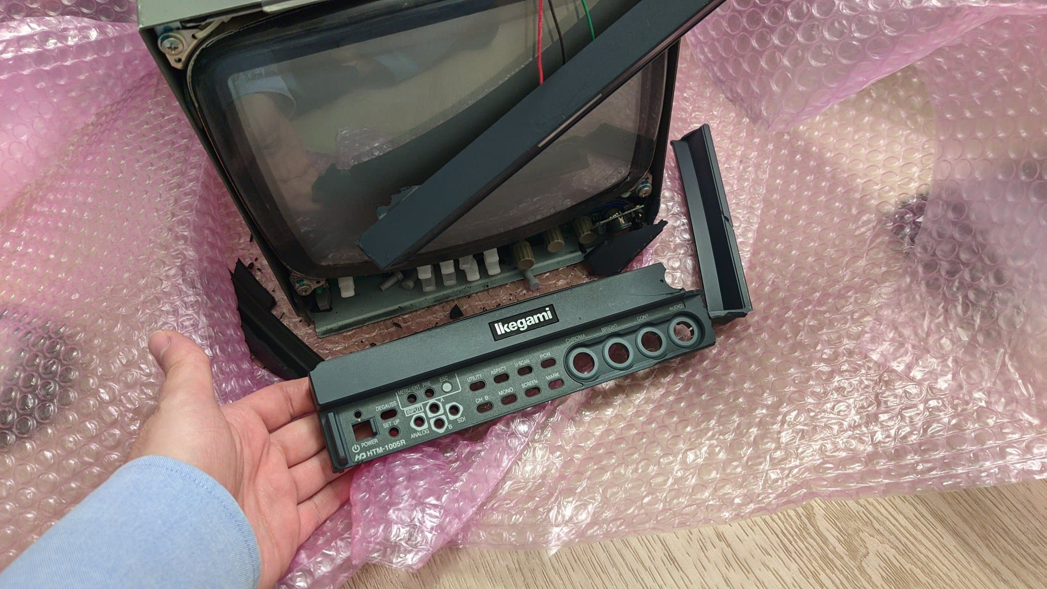Ikegami HTM-1005RA2 monitor disassembled showing CRT tube, circuit board, and control panel with input connectors during inspection after transit damage.