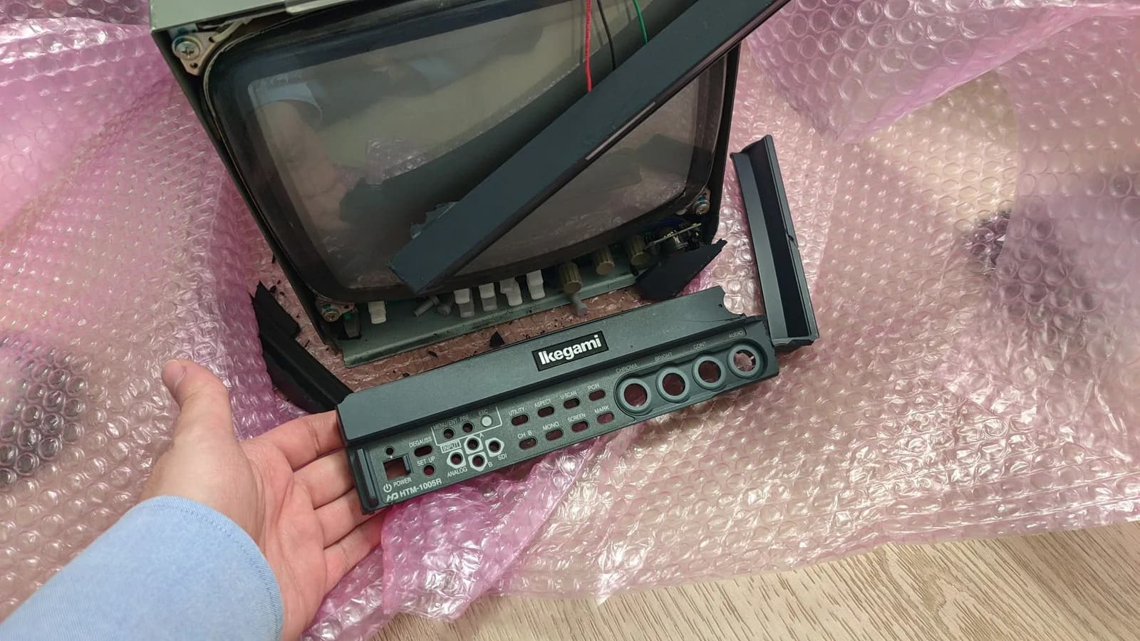 Ikegami HTM-1005RA2 monitor disassembled showing CRT tube, circuit board, and control panel with input connectors during inspection after transit damage.