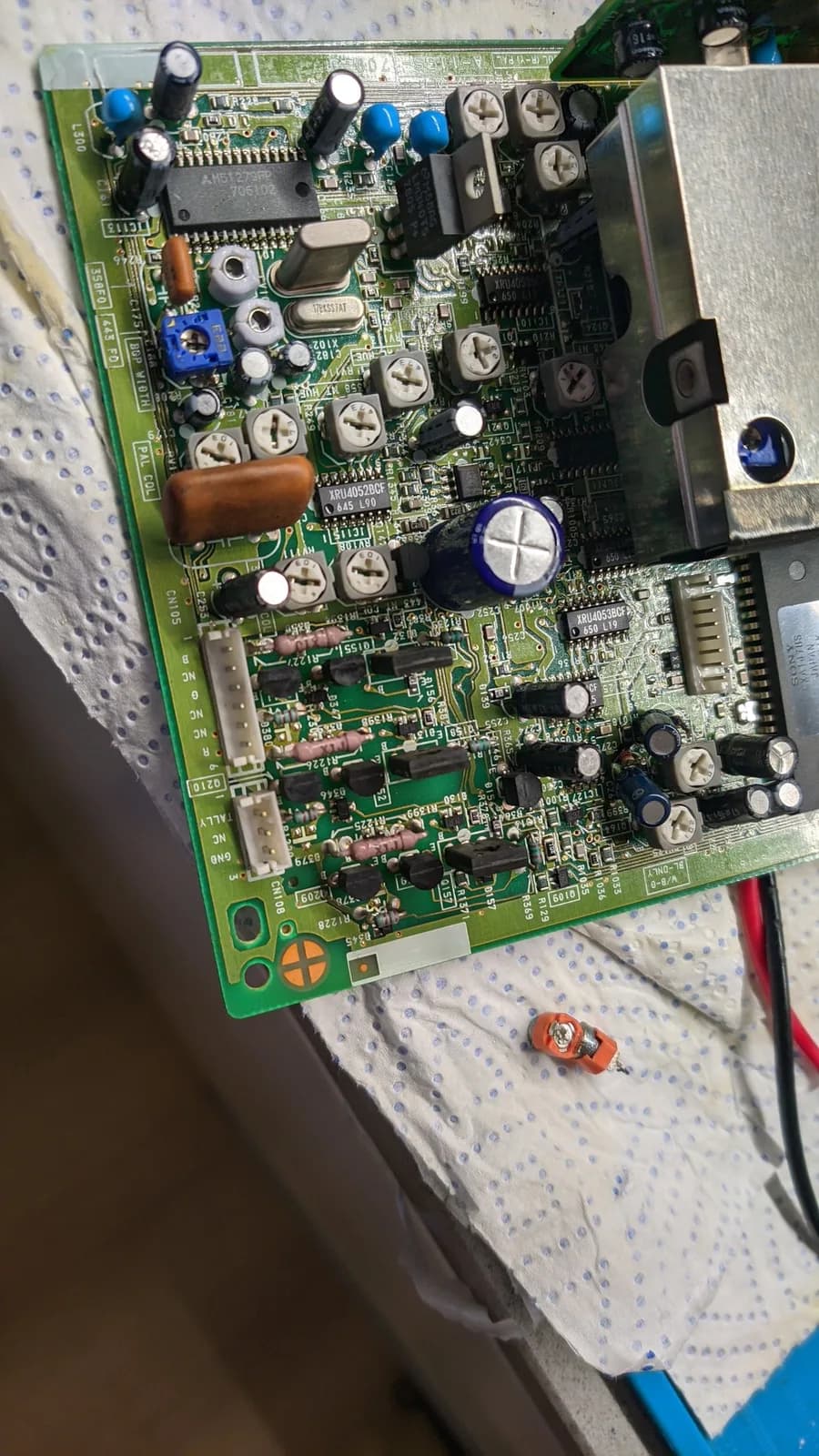 Sony PVM-9041Q B board (top side) with the new colour trimmer pots fitted and the old orange ones removed onto the white paper towel below, a metal shield over part of the board. This is the B board, not the PSU.