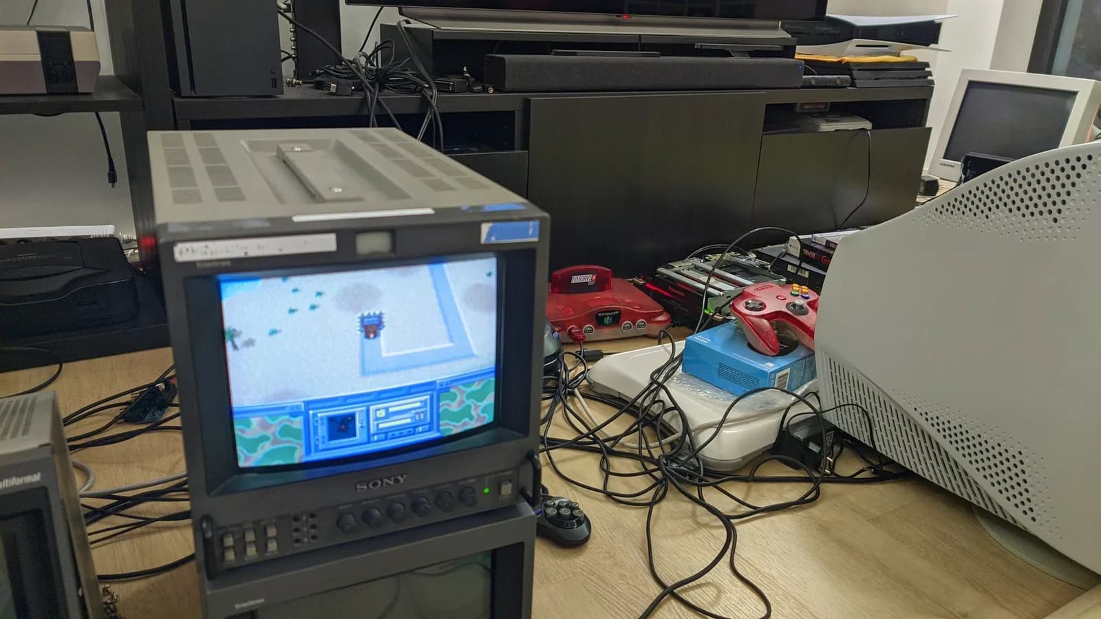 A Sony PVM-9041Q on the floor showing Return Fire, running from the Panasonic FZ-1 3DO via the ODE; the opened 3DO (top off, its red READY and green ACCESS LEDs lit) sits at the back beside a translucent red Nintendo 64, amid tangled cables.