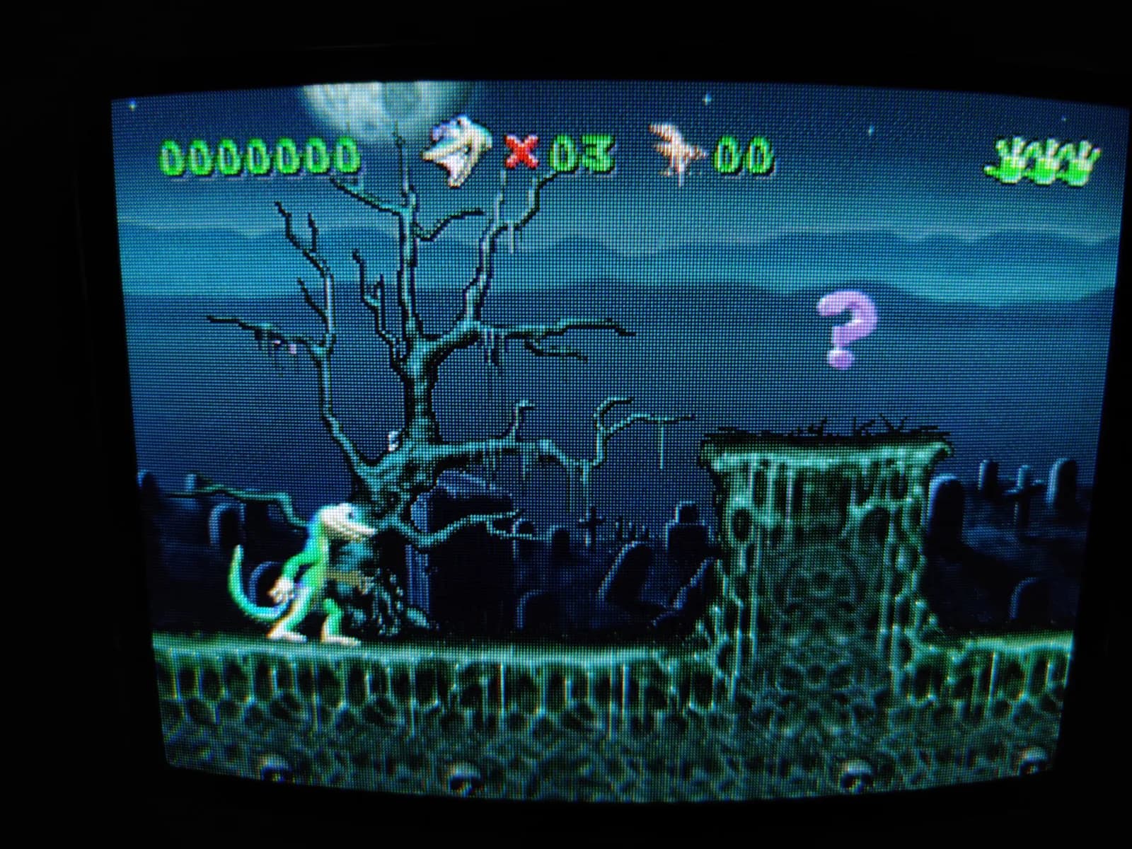 Gex running on the Panasonic FZ-1 3DO via the ODE, on a Sony PVM-9041Q: a night-time graveyard with a bare dead tree and gravestones, the green gecko standing on a stone ledge; the HUD shows a 0000000 score and 03 lives.