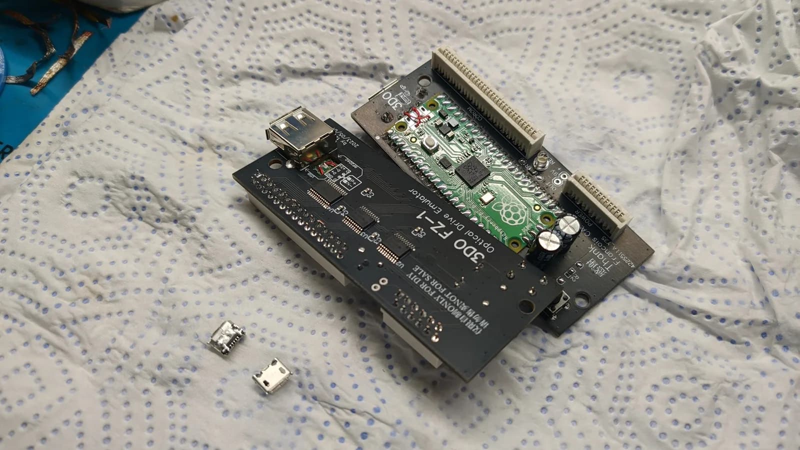 Two assembled 3DO FZ-1 ODE boards, one shown from the top and the other from the underside; a full-size USB-A port has been fitted, with the Raspberry Pi Pico's micro-USB rerouted by wires to the points on the ODE PCB where the USB-A is soldered.