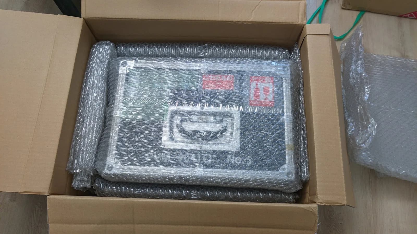 Sony PVM-9041Q as it arrived from Japan, bubble-wrapped in its hard transit case (stencilled PVM-9041Q) inside a cardboard box, Japanese handling stamps visible.