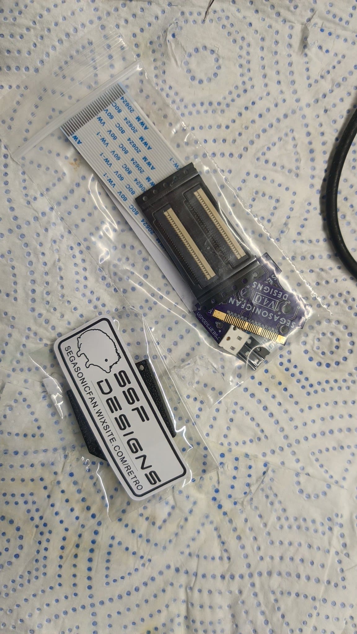 Virtual Ribbon 4.0 kit and mounting jig in packaging, showing connector assembly and installation documentation for Virtual Boy repair.