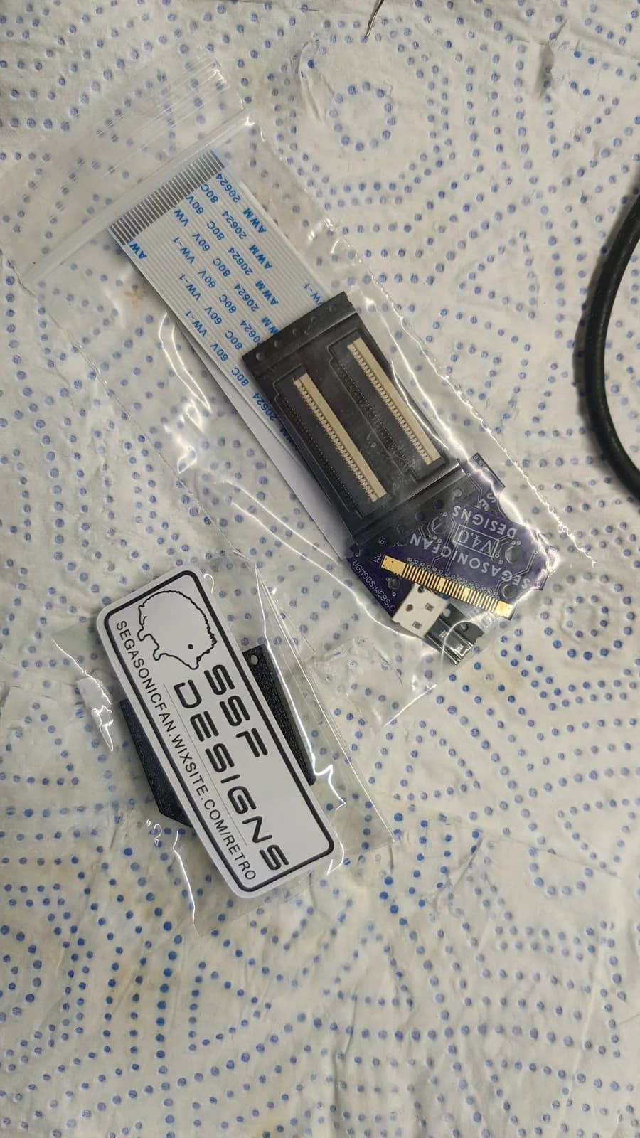 Virtual Ribbon 4.0 kit and mounting jig in packaging, showing connector assembly and installation documentation for Virtual Boy repair.