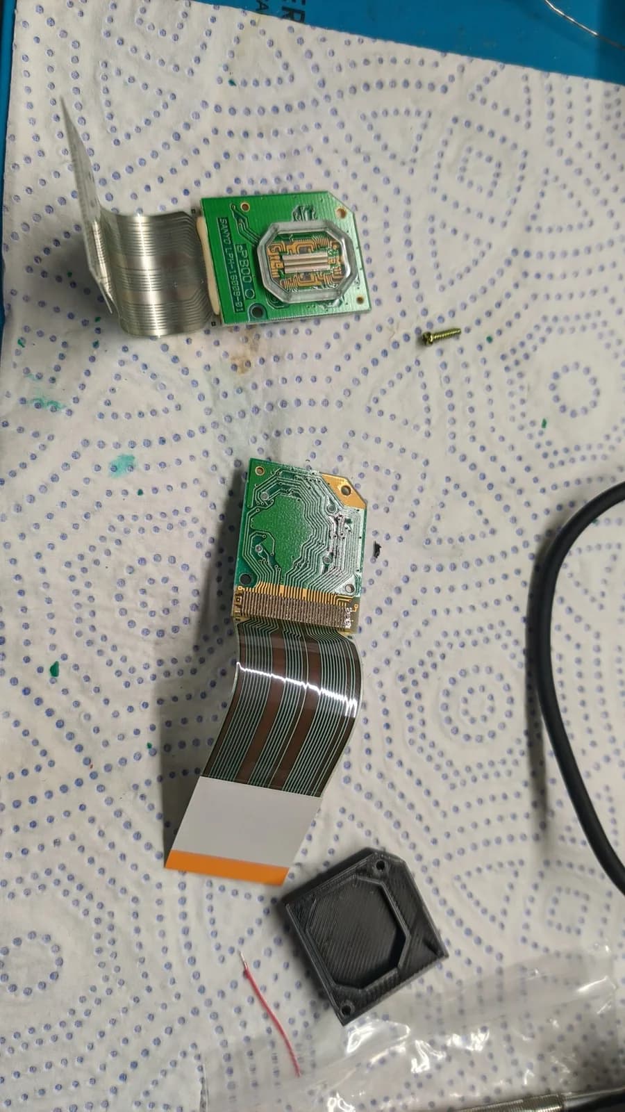 Disassembled Virtual Boy display components showing LED array PCBs with attached flex ribbons in various stages of separation and removal during refurbishment.