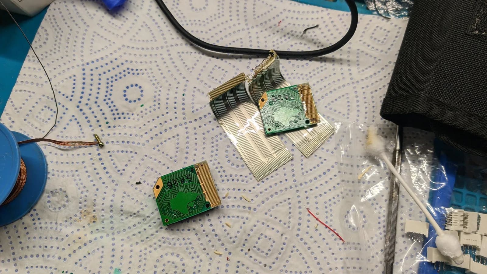 Two green LED array PCBs with flexible ribbon cables attached, one partially separated showing adhesive removal during Virtual Boy display refurbishment.