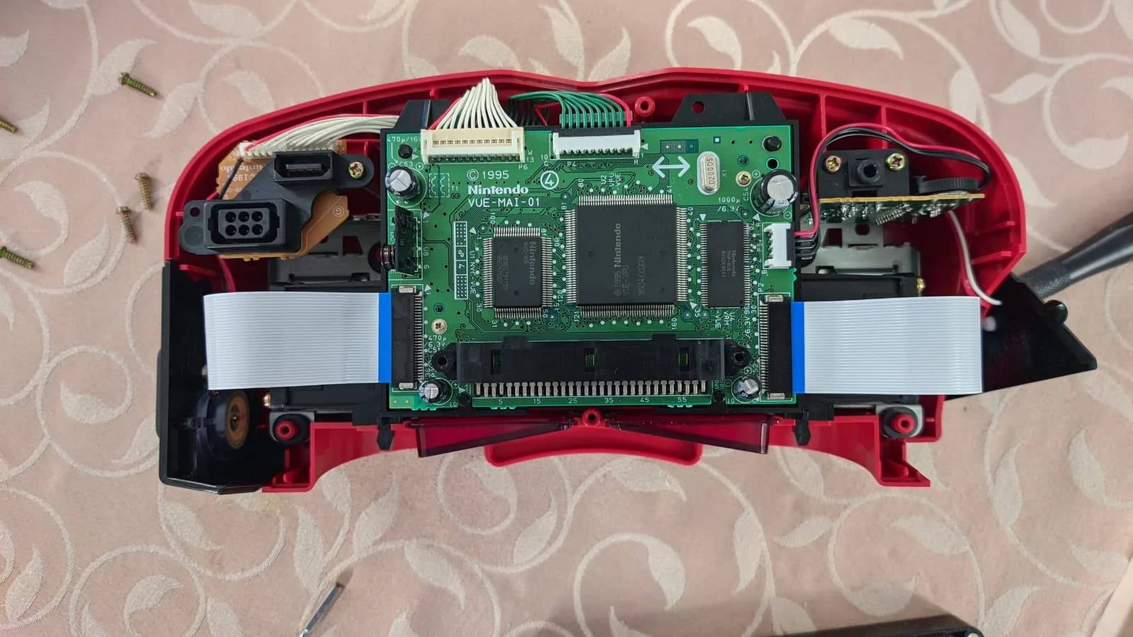 Nintendo Virtual Boy mainboard with VB 4.0 ribbon cable installed, showing uneven mounting jig pressure and soldering challenges on LED array connection points.
