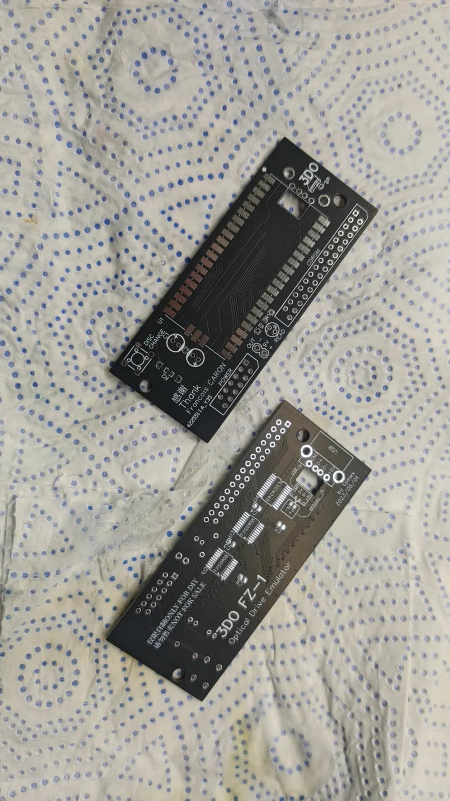 Two bare 3DO FZ-1 ODE PCBs on a paper towel, showing the silkscreen and pad footprints, including the "3DO FZ-1 Optical Drive Emulator" and "by tzmwx" markings.