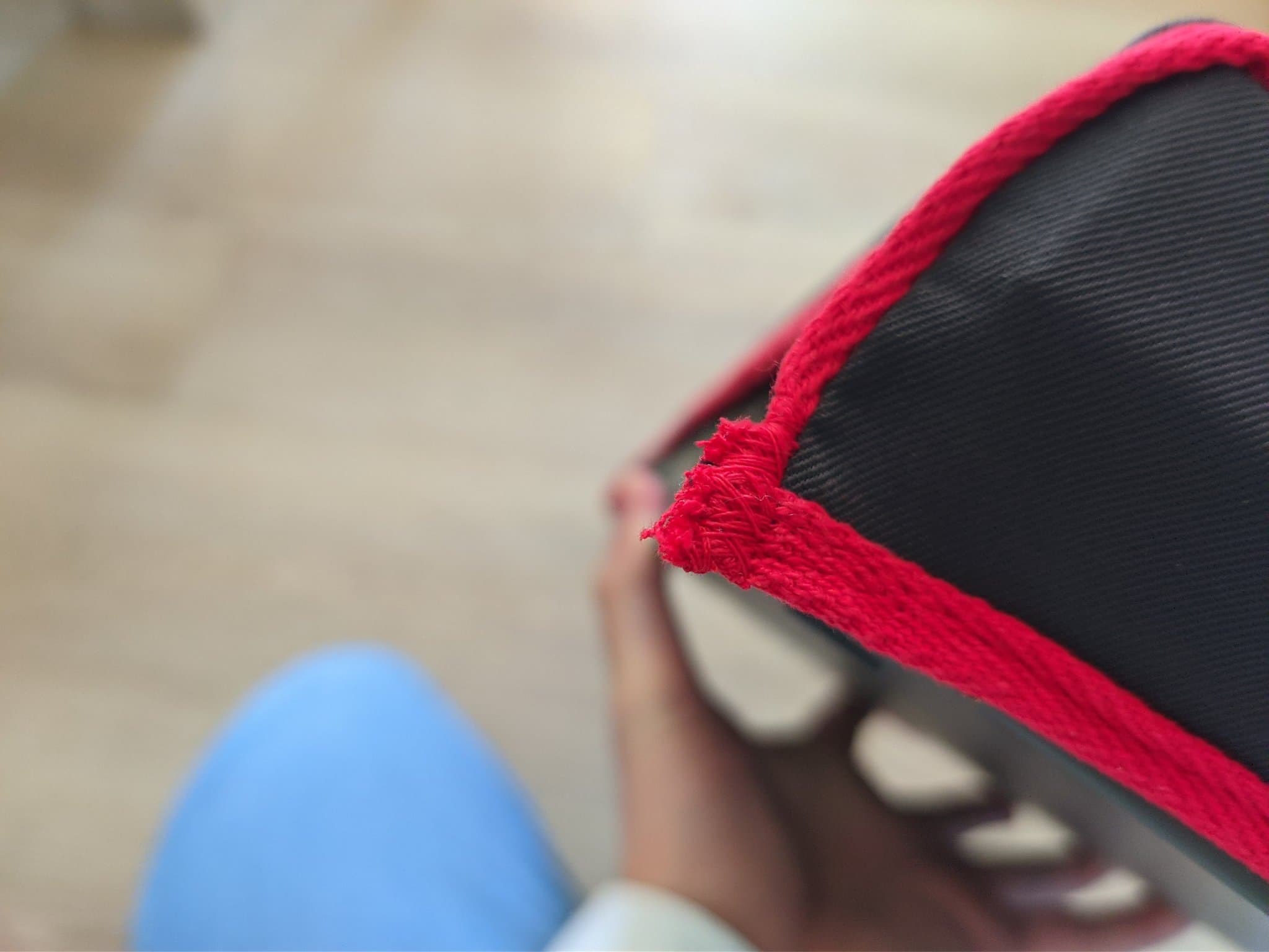 Close-up of frayed red fabric trim on black ZX Spectrum +2 dust cover, showing poor finishing quality.