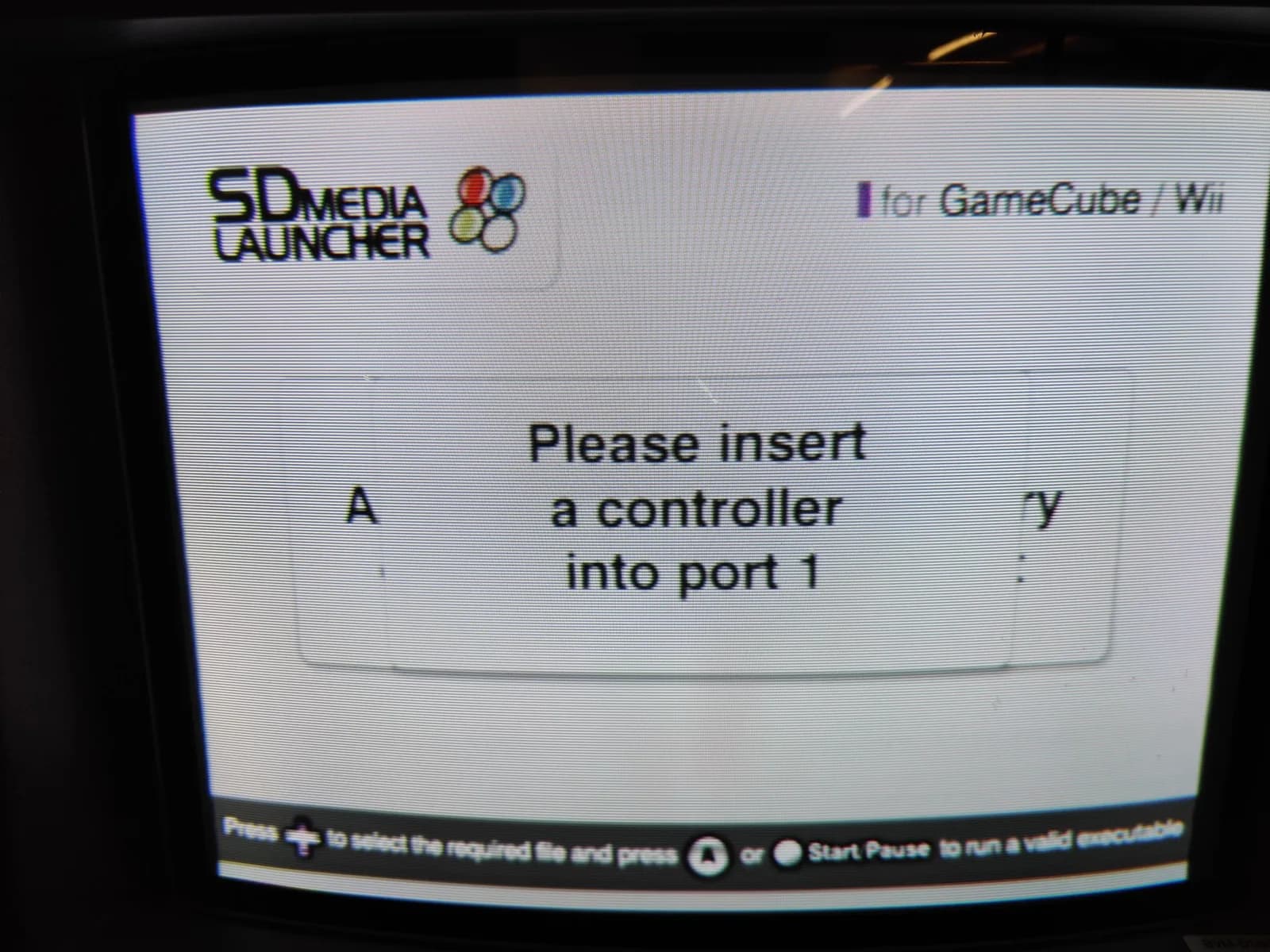 The Datel SD Media Launcher homebrew loader on a GameCube showing 'Please insert a controller into port 1' with its 'for GameCube / Wii' badge, booted from disc, confirming the drive reads discs again after the lid-switch fix and recap, on the optical-drive recap day.