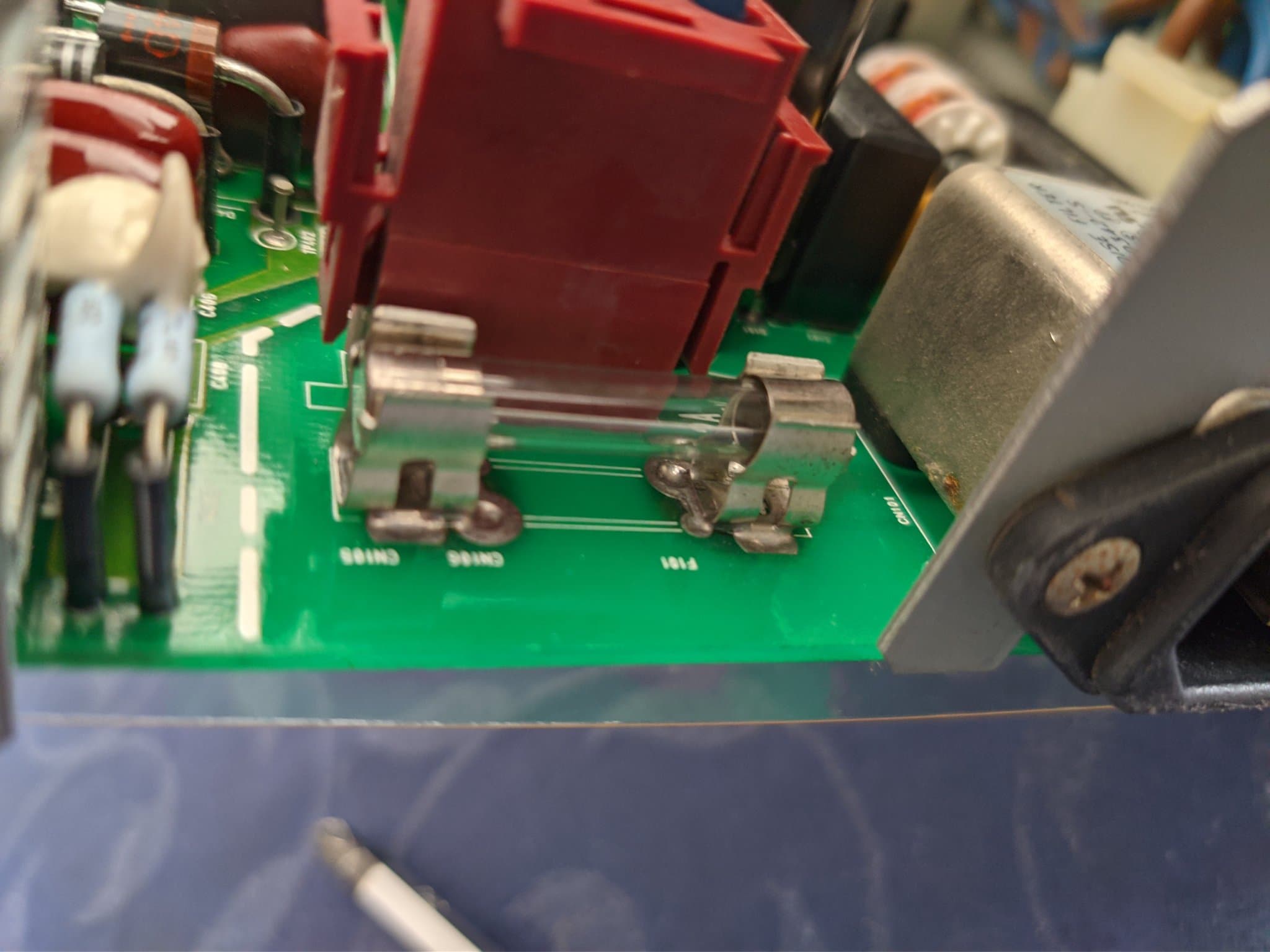 Close-up of the Ikegami TM10-17RA PSU board at the F101 fuse in its spring clips, beside a maroon mains connector and CN106 and CN108 headers.