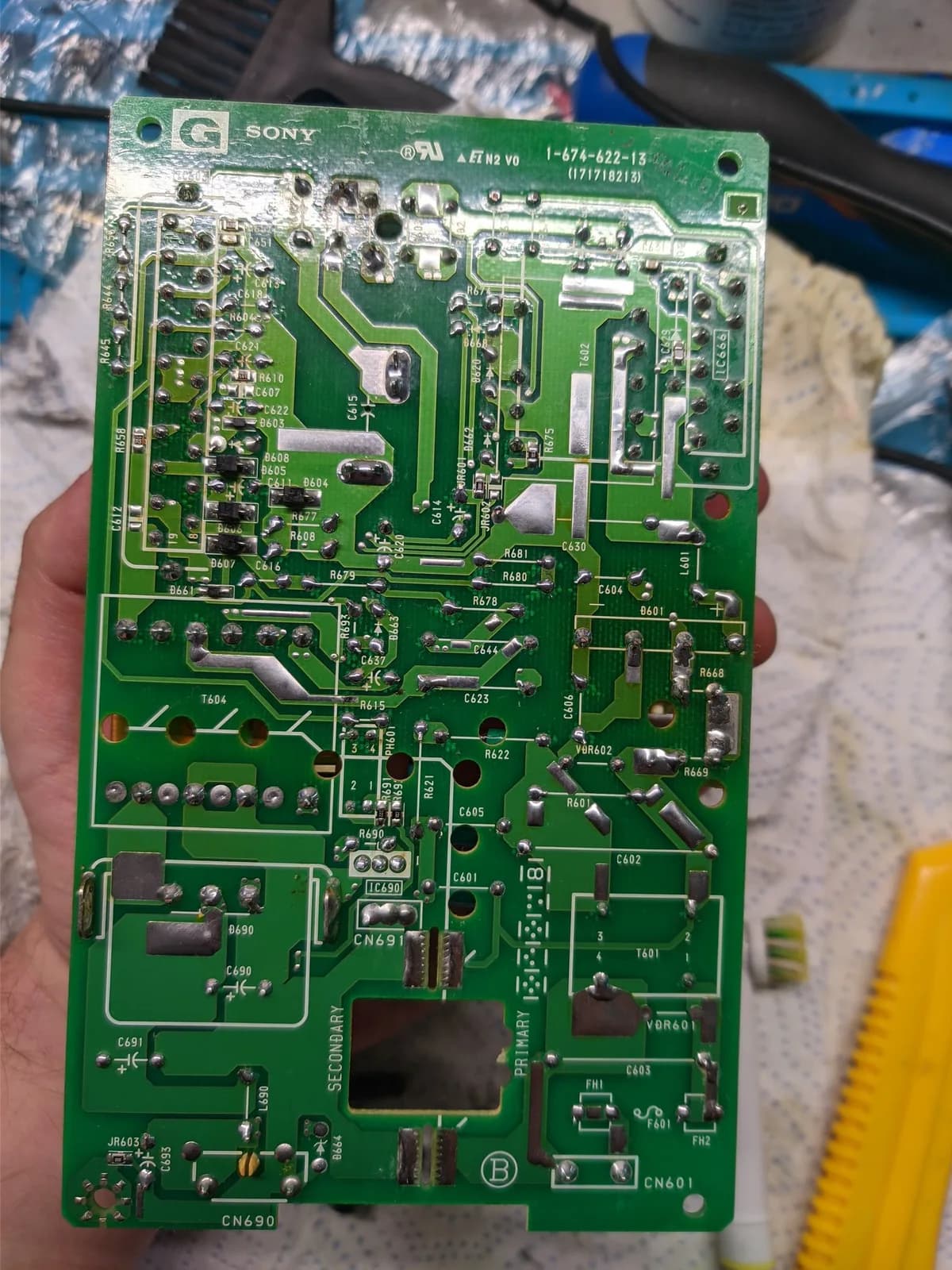 Solder side of the Sony BVM-D9H5J power supply board, held up to show every joint reflowed by hand, solder joints and traces visible, with the 'SONY' mark, part number 1-674-622-15 and 'PRIMARY'/'SECONDARY' silkscreen.