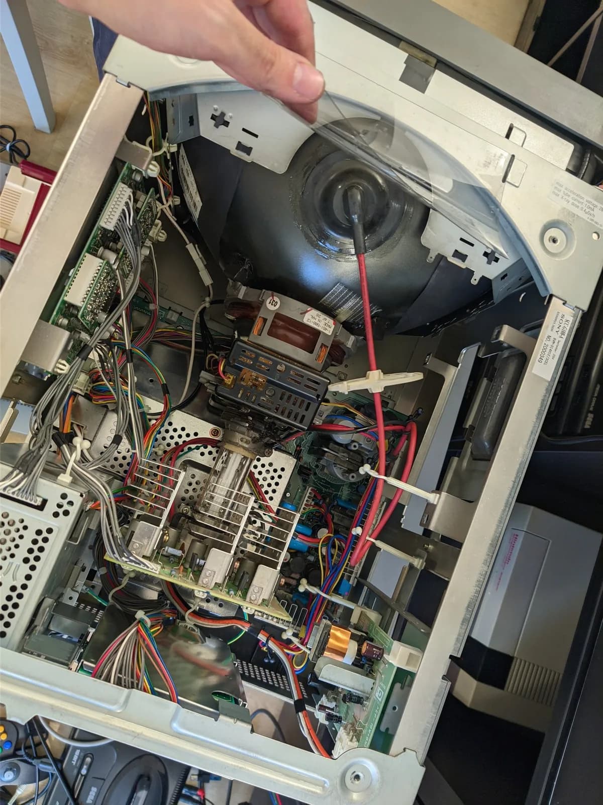 Interior of the reassembled and cleaned Sony BVM-D14H1E: the CRT neck and deflection yoke, the flyback transformer and the red high-voltage anode lead with dielectric grease visible around the anode cap, dense wiring across the boards; a chassis label reads BVM-D14H1E.