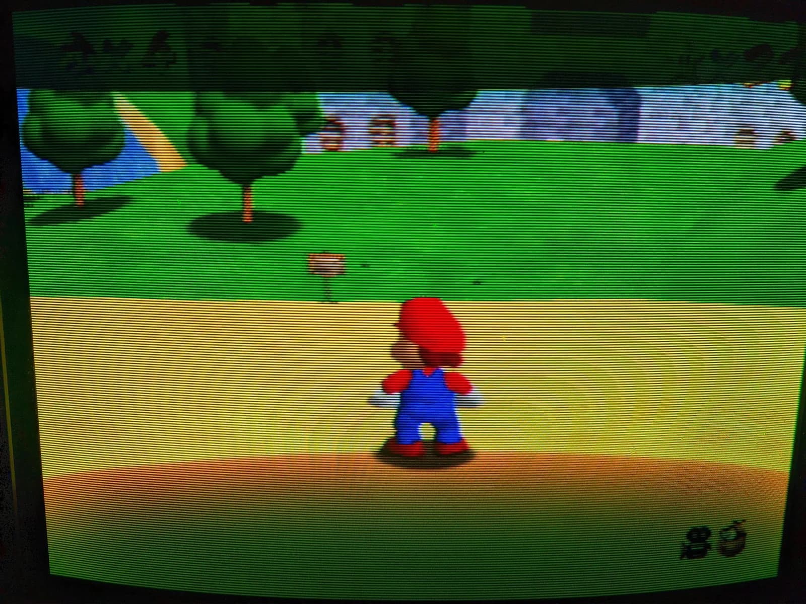 Super Mario 64 on the Sony BVM-D14H1E, the 3D Mario seen from behind on a grassy field, run from an N64 over composite through the BKM-127W decoder, CRT scanlines across the image.
