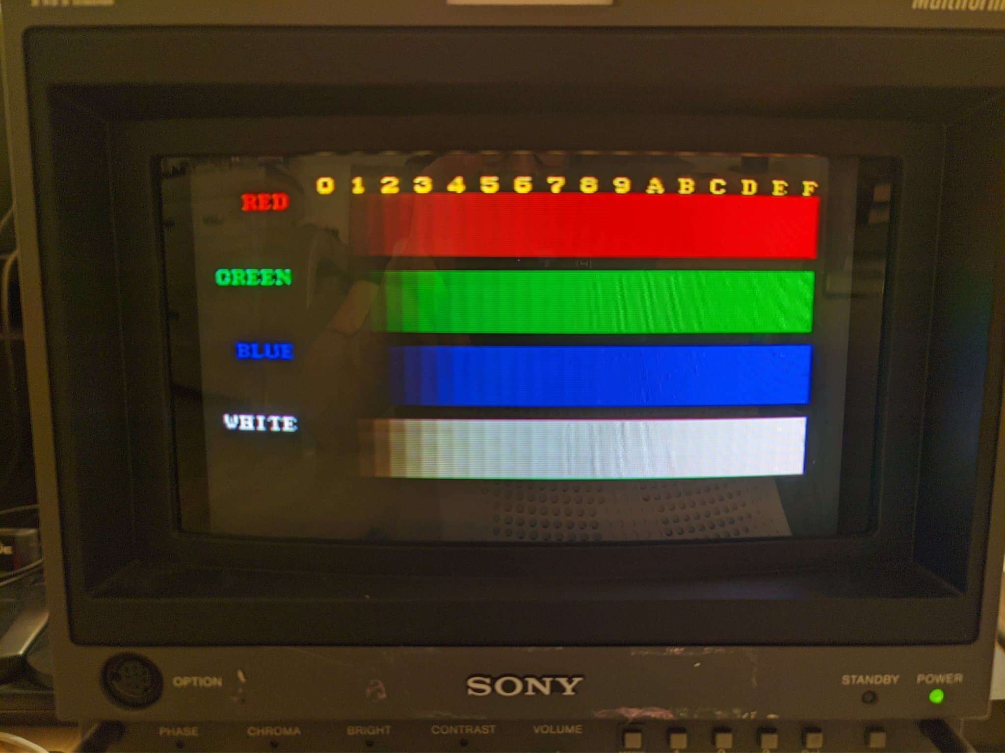 Sony BVM-D9H5J displaying color bars test pattern: red, green, blue, and white stripes with hexadecimal reference numbers across top.