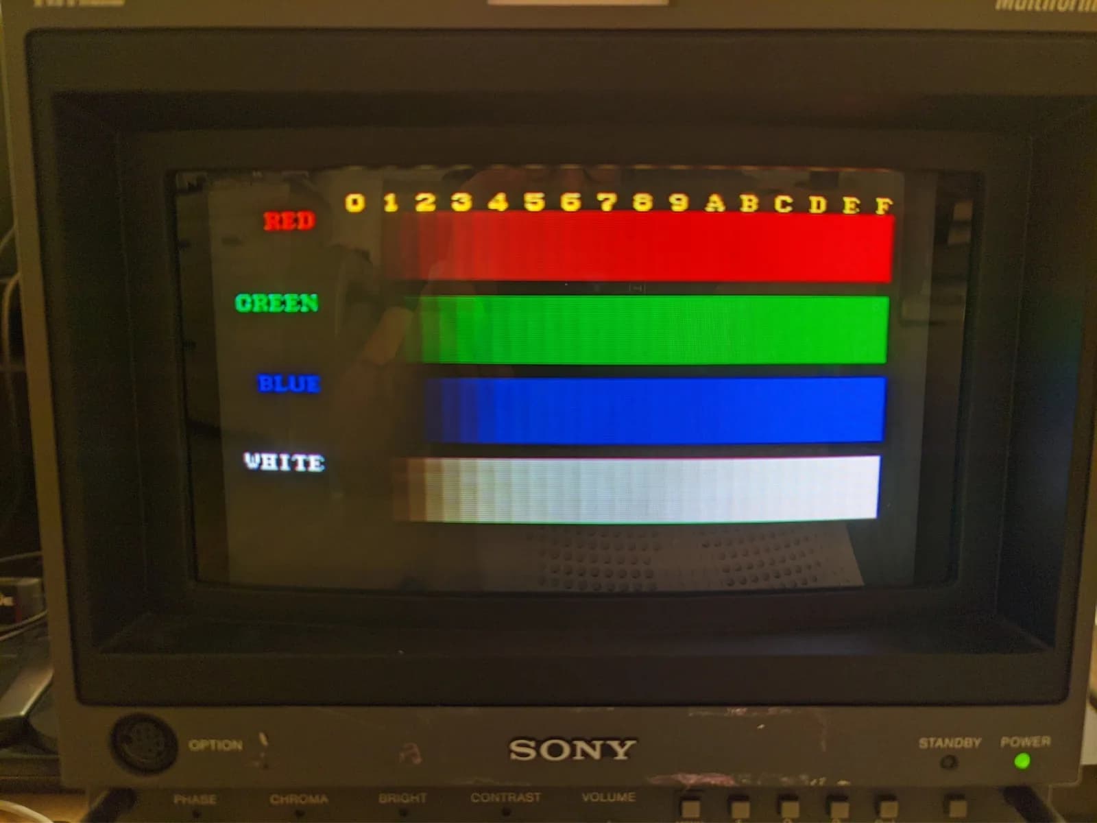 Sony BVM-D9H5J displaying a colour-bars test pattern (red, green, blue and white bars), the blue visibly weaker than the others, showing the colour imbalance on the aged tube.