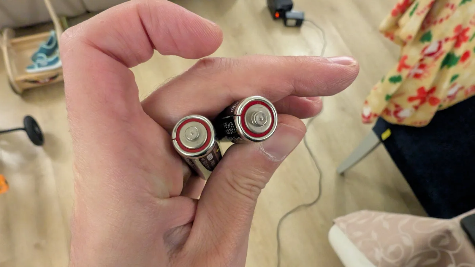 Close-up of two Hudson Soft branded AA batteries held in palm, showing original factory components from Ten No Koe 2 handheld device.