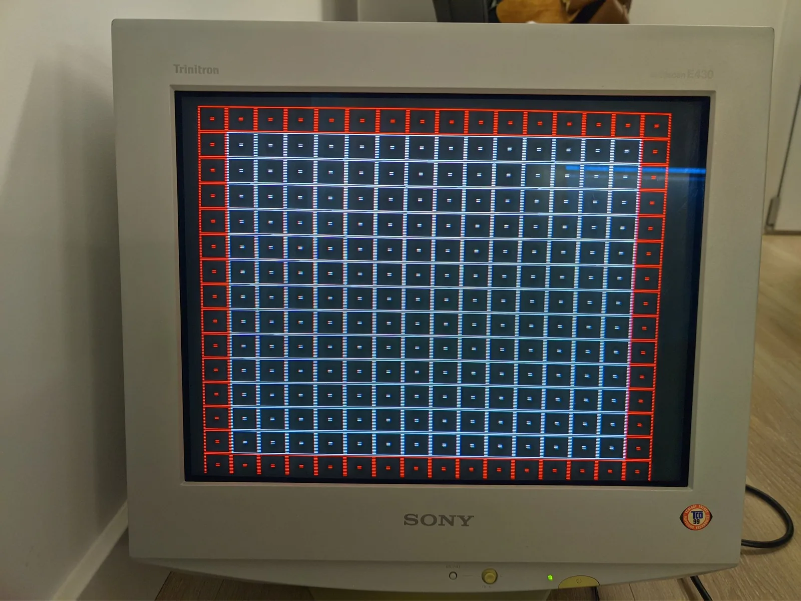 Sony CPD-E430 CRT displaying red and blue grid pattern test screen on Trinitron monitor during diagnostics.