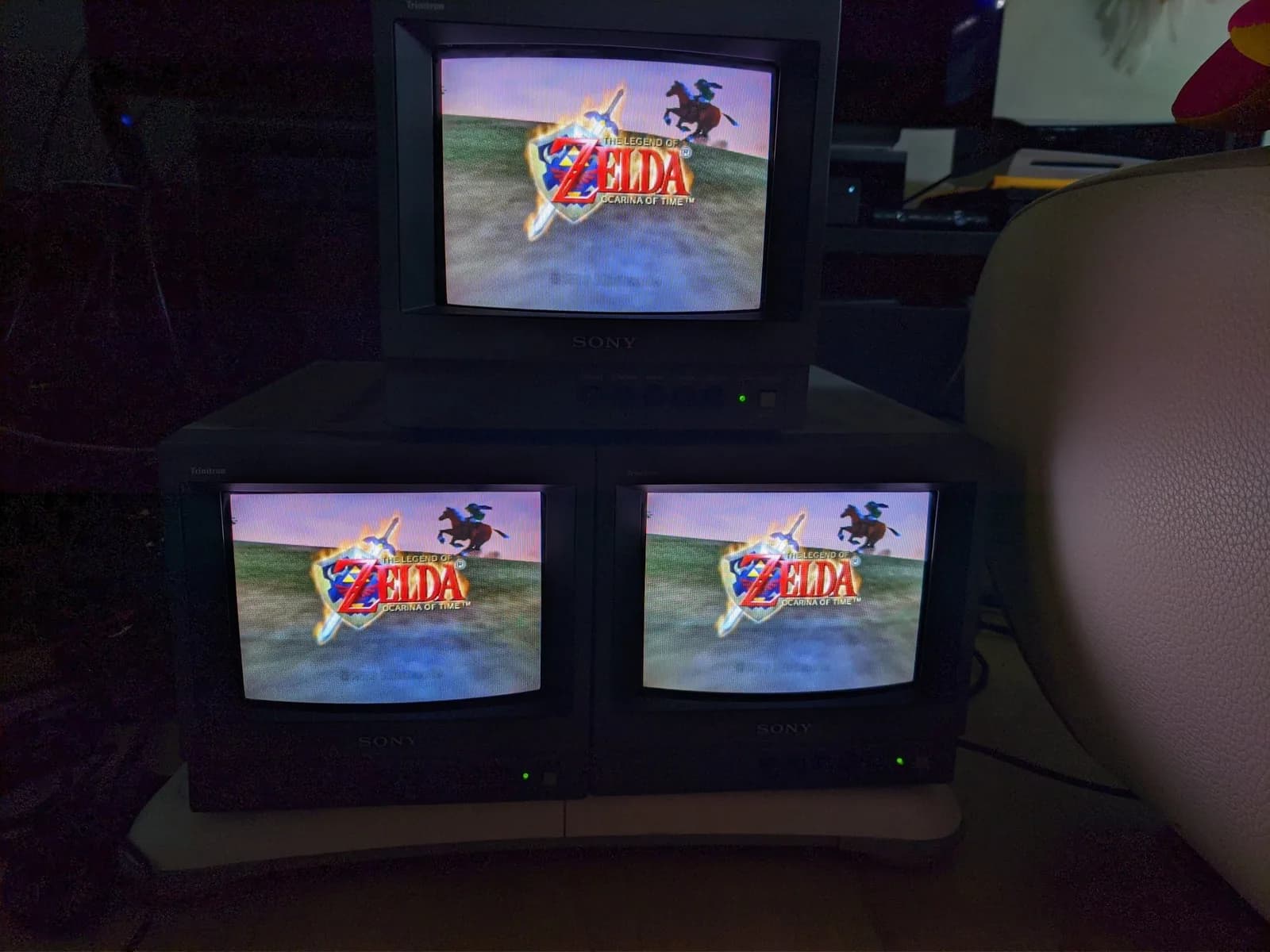 Three Sony PVM-9040 CRT monitors displaying Zelda: Ocarina of Time title screen, demonstrating color restoration after potentiometer and capacitor replacement.