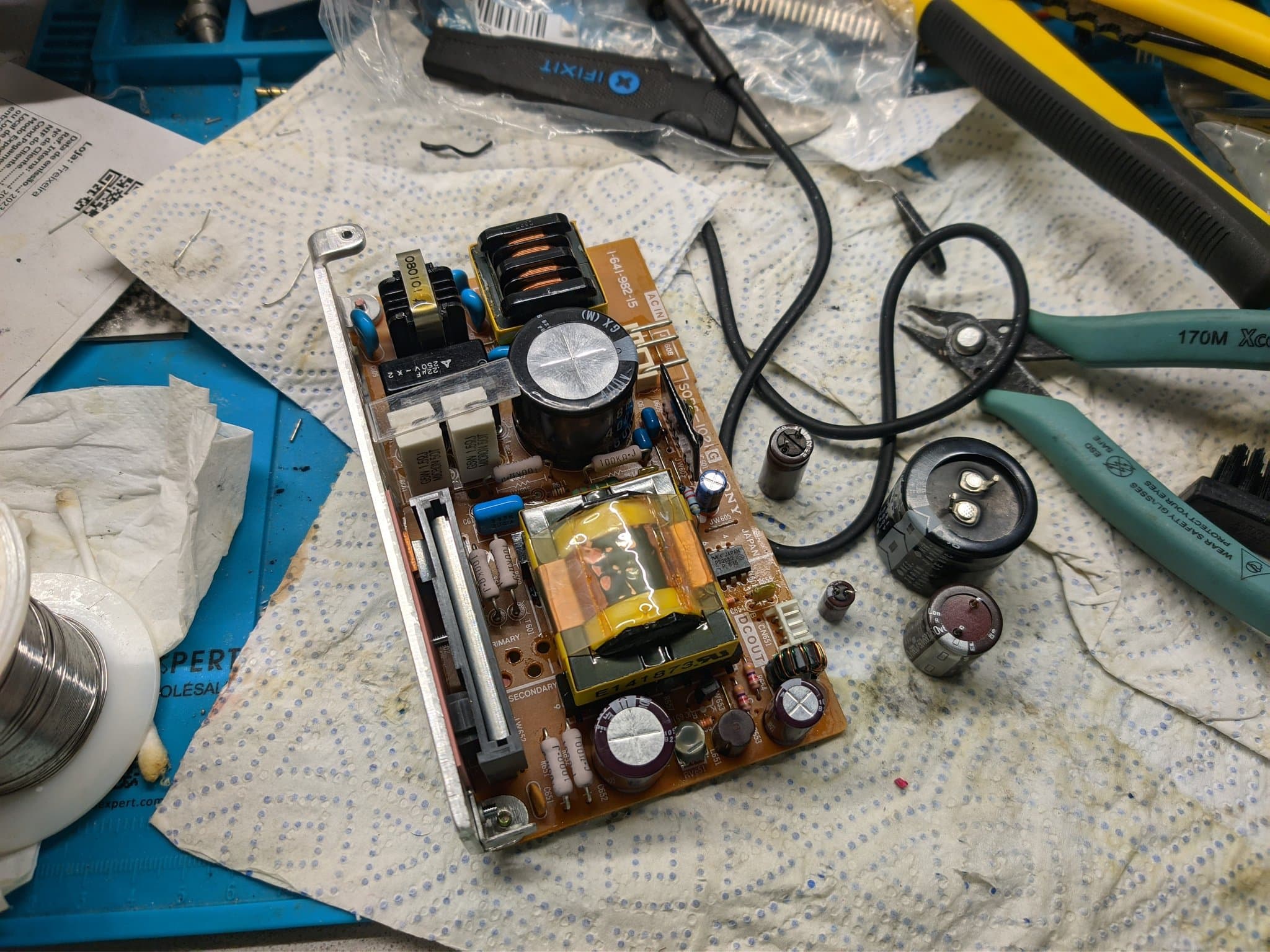 Disassembled Sony PVM-9040 PSU board showing capacitors, transformers, and inductors during inspection; no visibly bulging capacitors present.