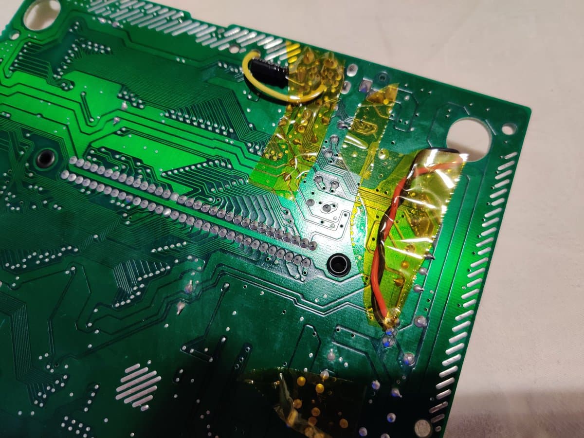 Close-up of Mega Drive RGB bypass mod installation showing soldered connections, yellow capacitors, red/black wires, and circuit board traces with slight picture oscillation noted.