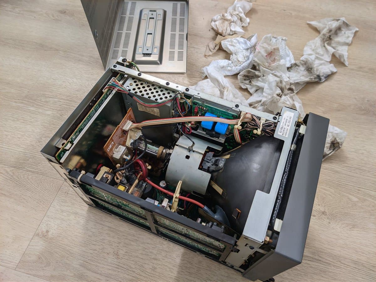 Disassembled Sony BVM-9045QD showing internal nicotine-stained components: PSU, deflection board, motor assembly, and heavy dust/tar buildup from chain smoking environment.