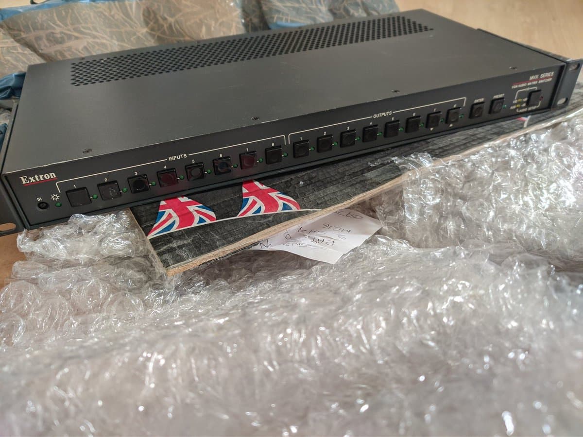 Extron MVX series video switch with 8 inputs and 8 outputs, still in protective bubble wrap packaging during setup.