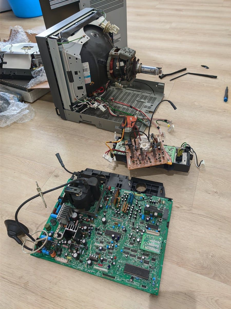 Disassembled Sony PVM-14M4J showing main board, deflection board, and motor assembly during retrace line repair with capacitor kit replacement.