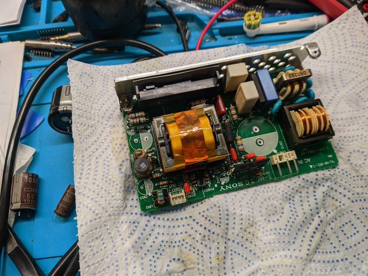 Sony BVM-9045QD PSU board with replaced electrolytic capacitors, showing yellow transformer, inductor coils, and new capacitors installed during recapping restoration.