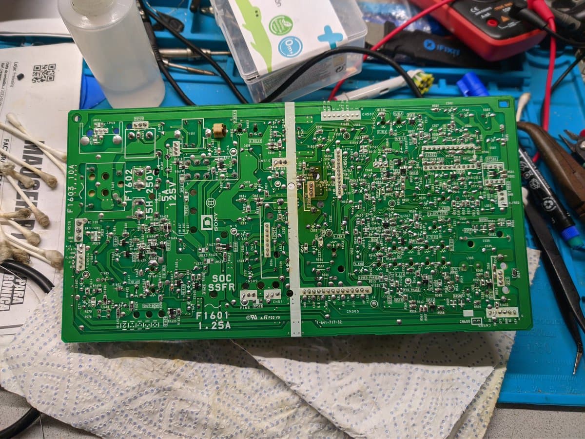 Sony BVM-9045QD deflection board (D board) with reflowed solder joints during restoration, surrounded by repair documentation and tools.