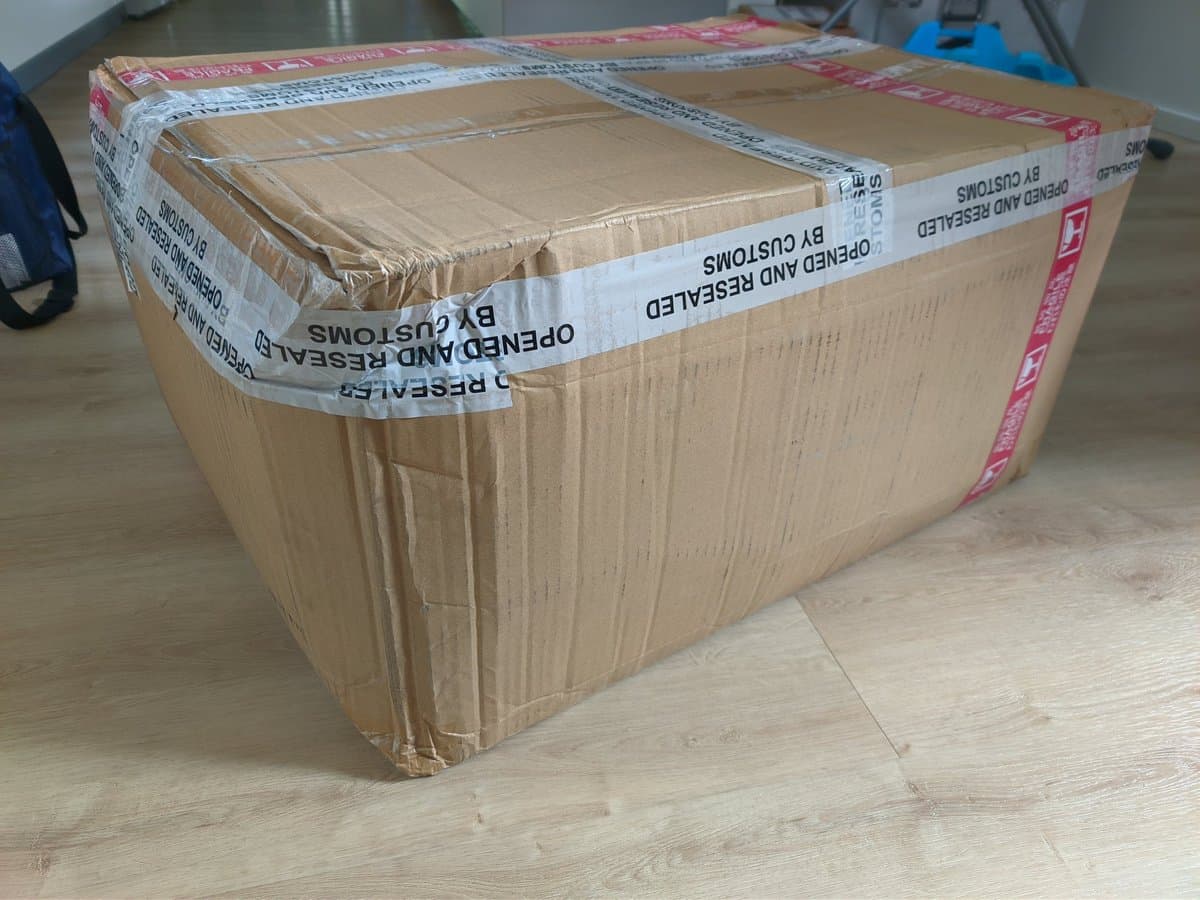 Damaged cardboard shipping box containing three Sony PVM-9040 CRT monitors, taped with customs inspection labels, no protective foam padding visible.