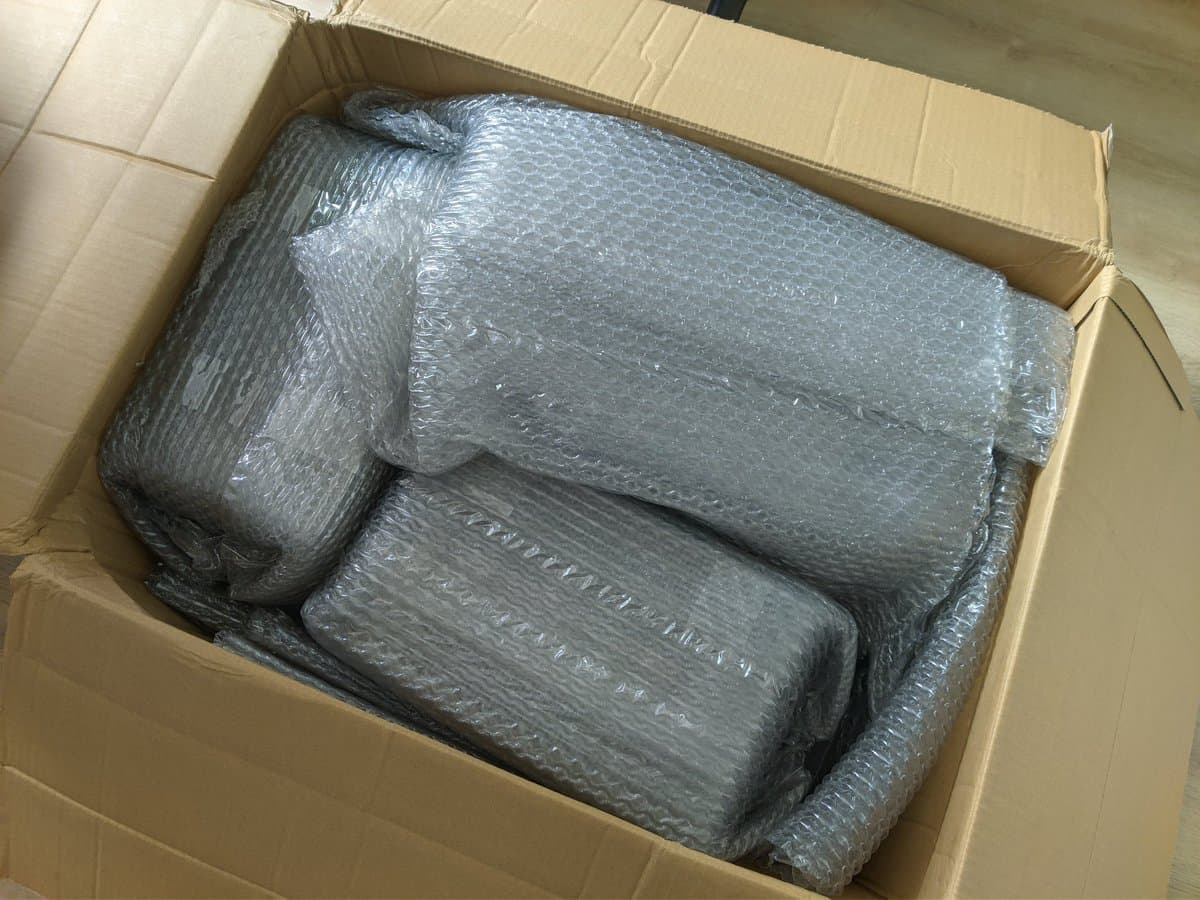 Three Sony PVM-9040 monitors wrapped in bubble wrap inside a cardboard shipping box, showing minimal packaging protection.