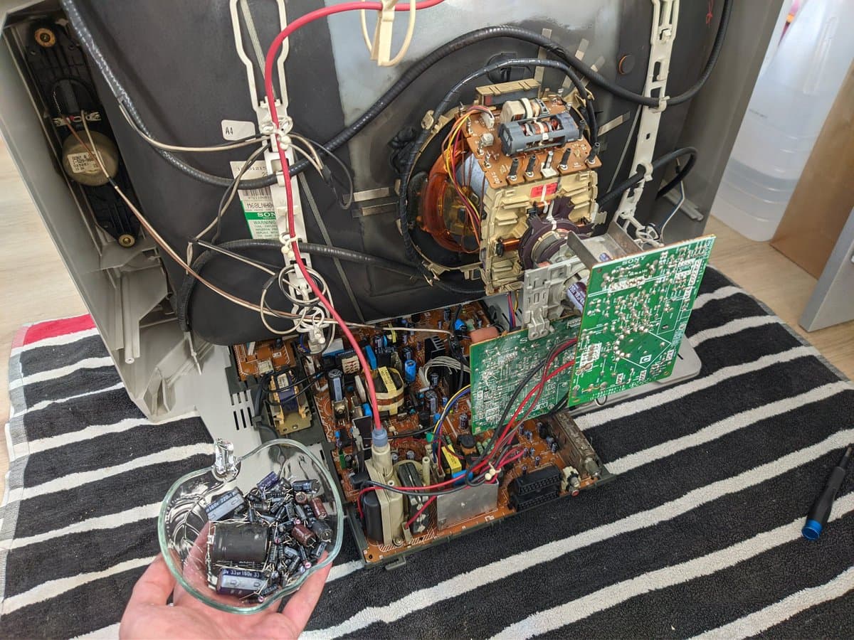 Disassembled Sony KV-29FX30E CRT internals showing recapped power supply and main boards with transformer, capacitors, and circuitry during restoration work.