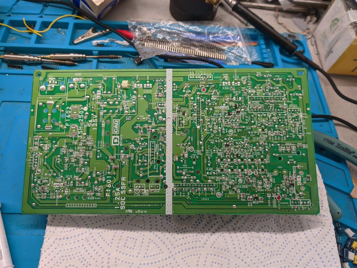 Sony PVM-9040 deflection board laid flat on workbench with soldering tools and replacement components nearby for repair.