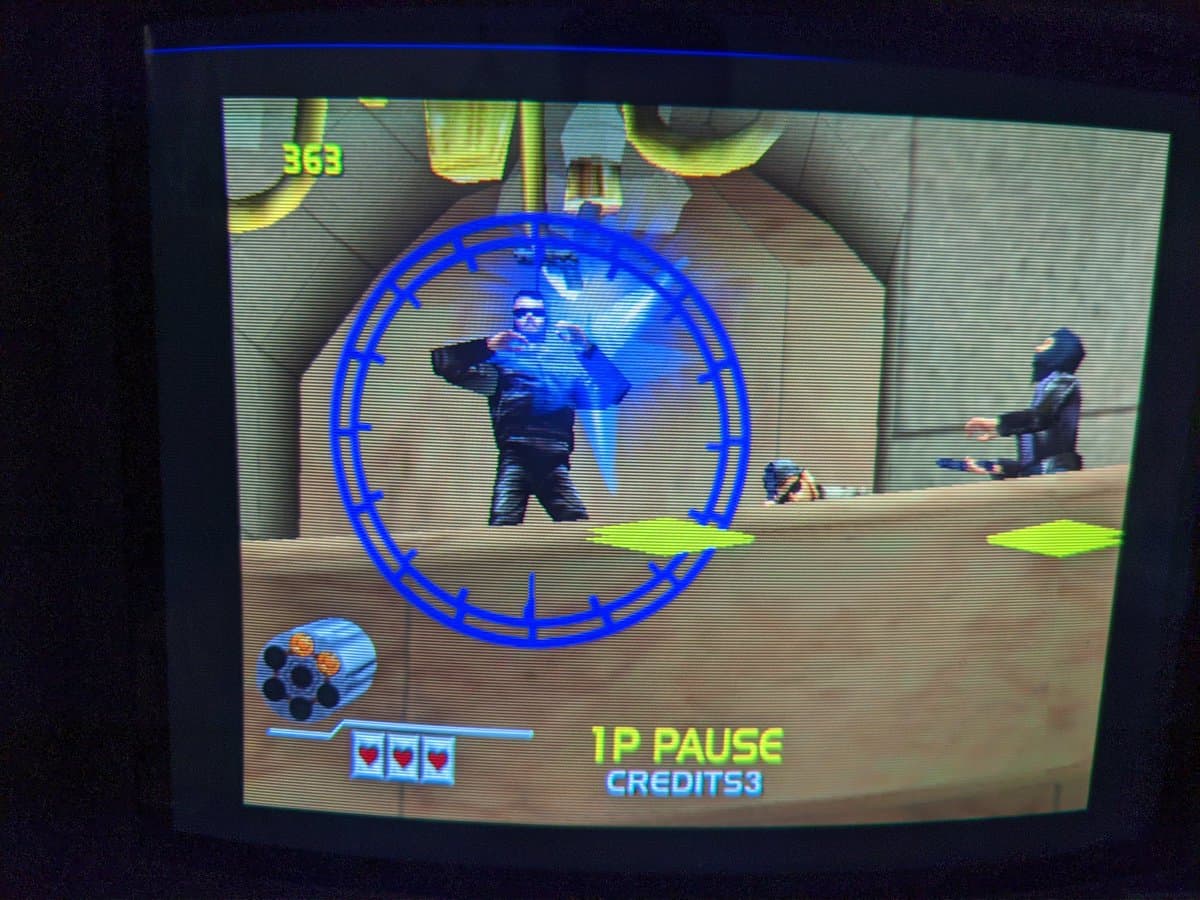 GunCon 2 test gameplay showing Virtua Cop Rebirth with targeting reticle active, HUD displaying 3 health points and 53 credits remaining.
