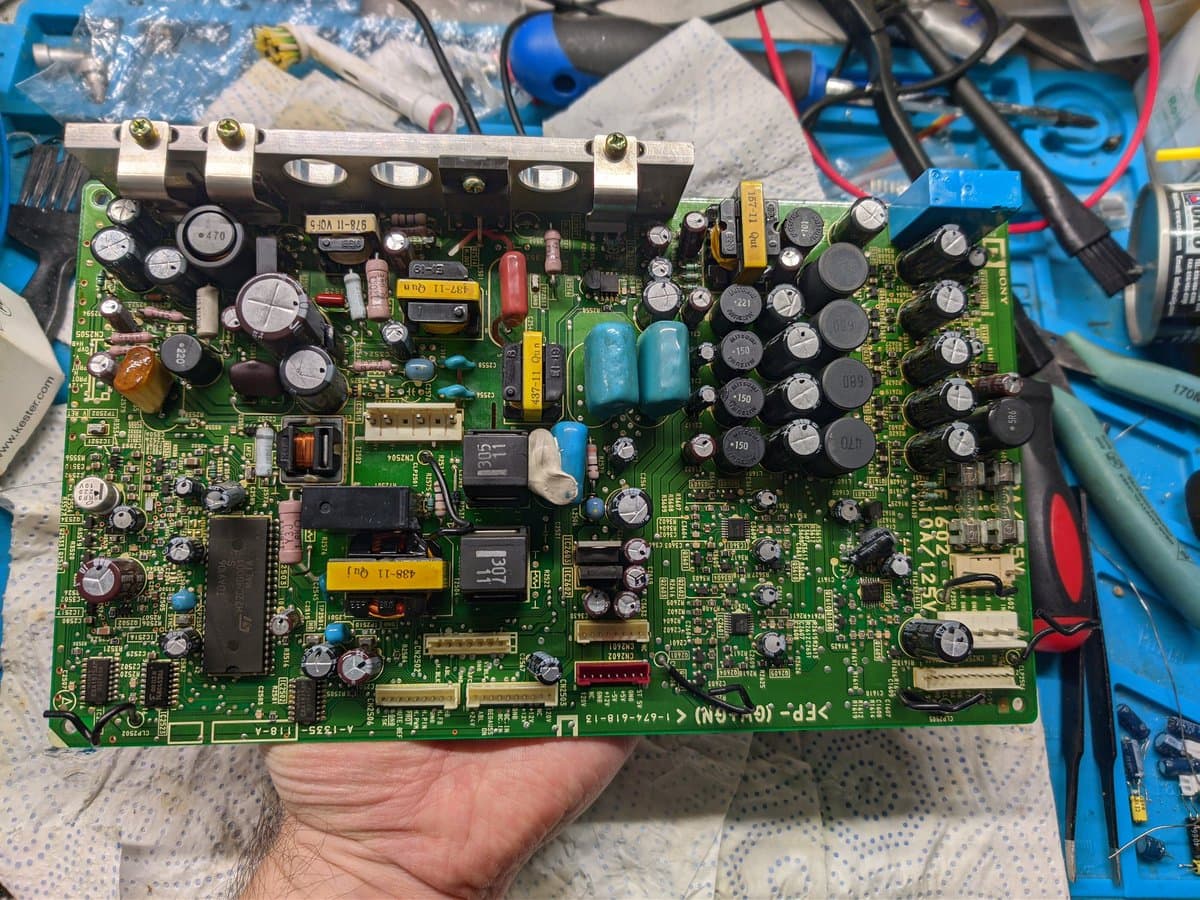 Sony BVM power supply board with poor solder joints, sticky flux residue, and reworked capacitor eyelets during restoration cleaning.