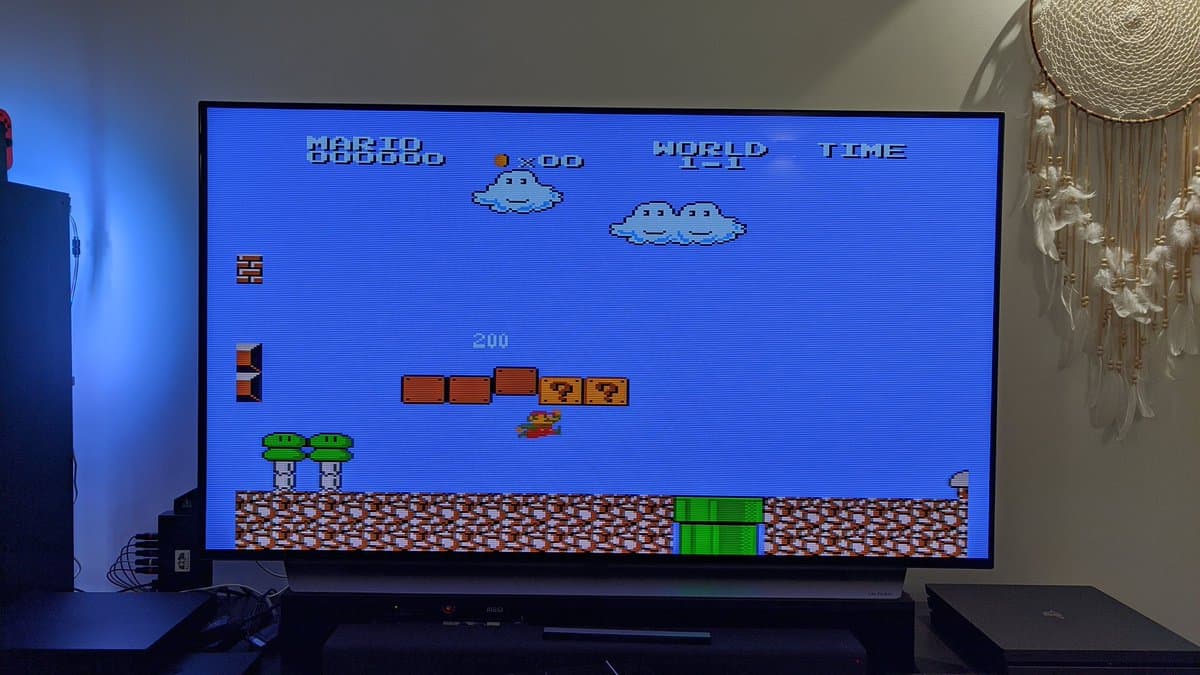 Twin Famicom displaying Super Mario Bros on CRT monitor with NESRGB mod installed, wireless controller in use.
