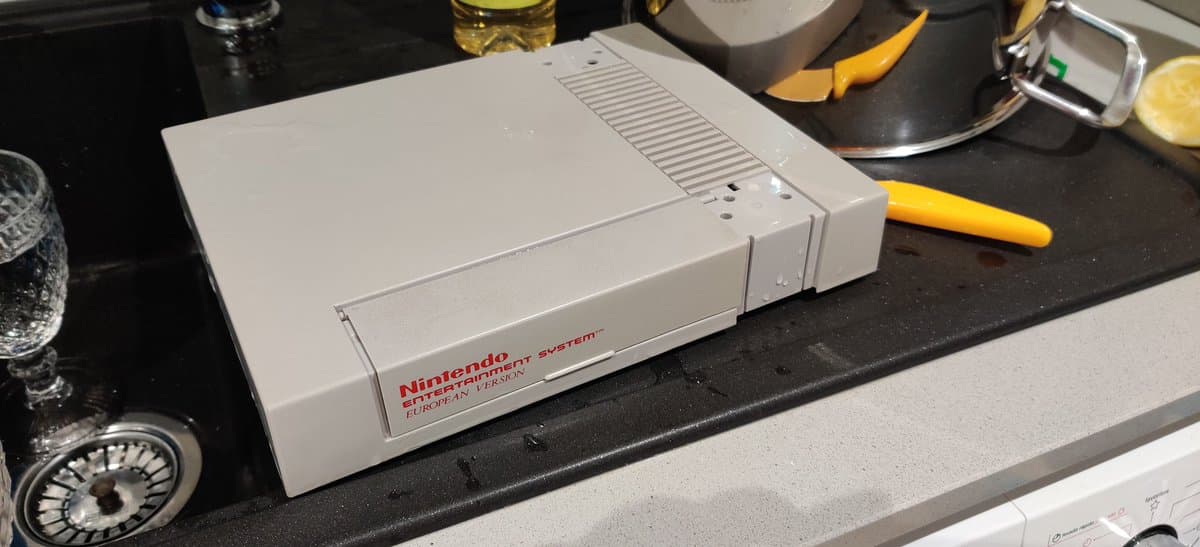 Nintendo Entertainment System European version on black desk surface surrounded by retrobriting supplies and tools.