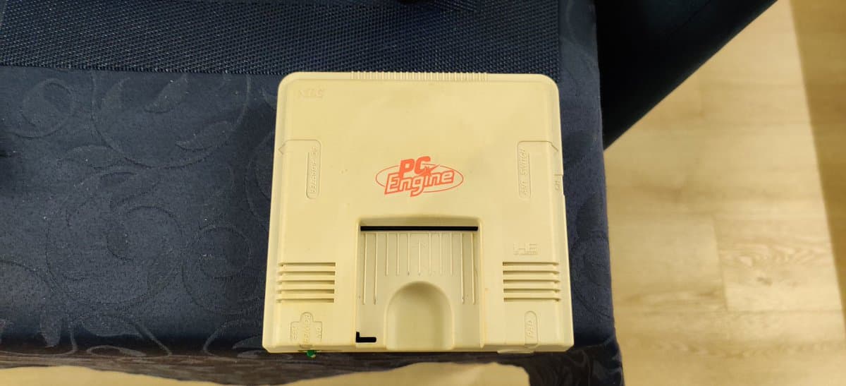 PC Engine console shell undergoing retrobrighting treatment, showing yellowed cream plastic before restoration.