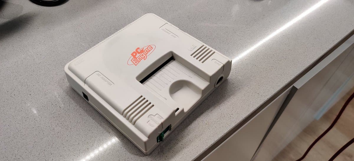 White PC Engine console with red logo undergoing retrobrighting treatment, displayed on work surface.