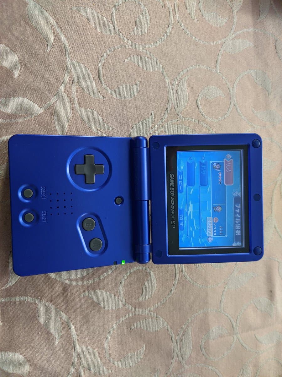 Blue Game Boy Advance SP open with display showing Zelda game, single electrolytic capacitor recapped, ready for continued use.