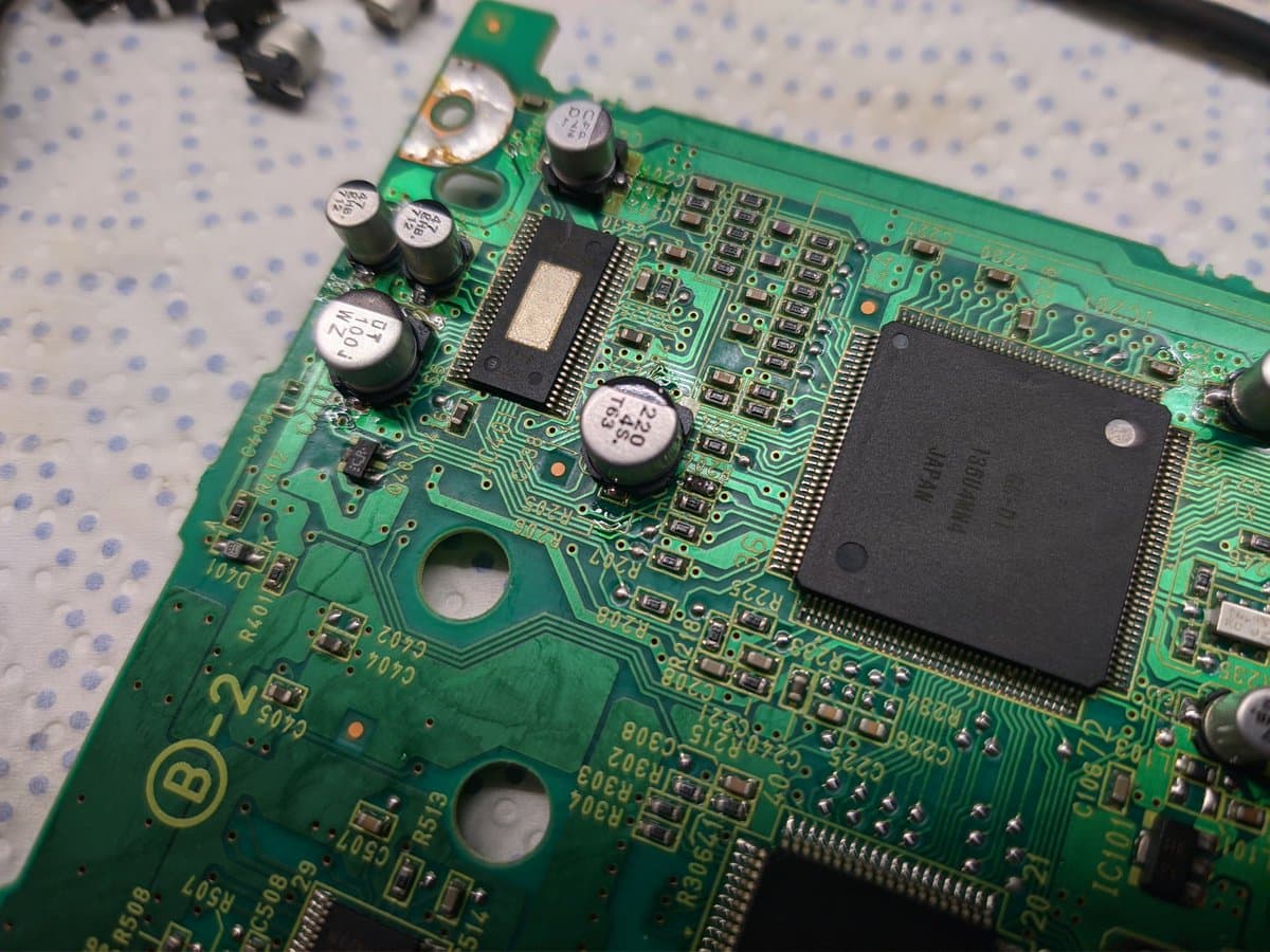 GameCube optical drive circuit board with recapped electrolytic capacitors and restored resistor; motor testing shows 30 ohms on failed drive versus OL on working unit.