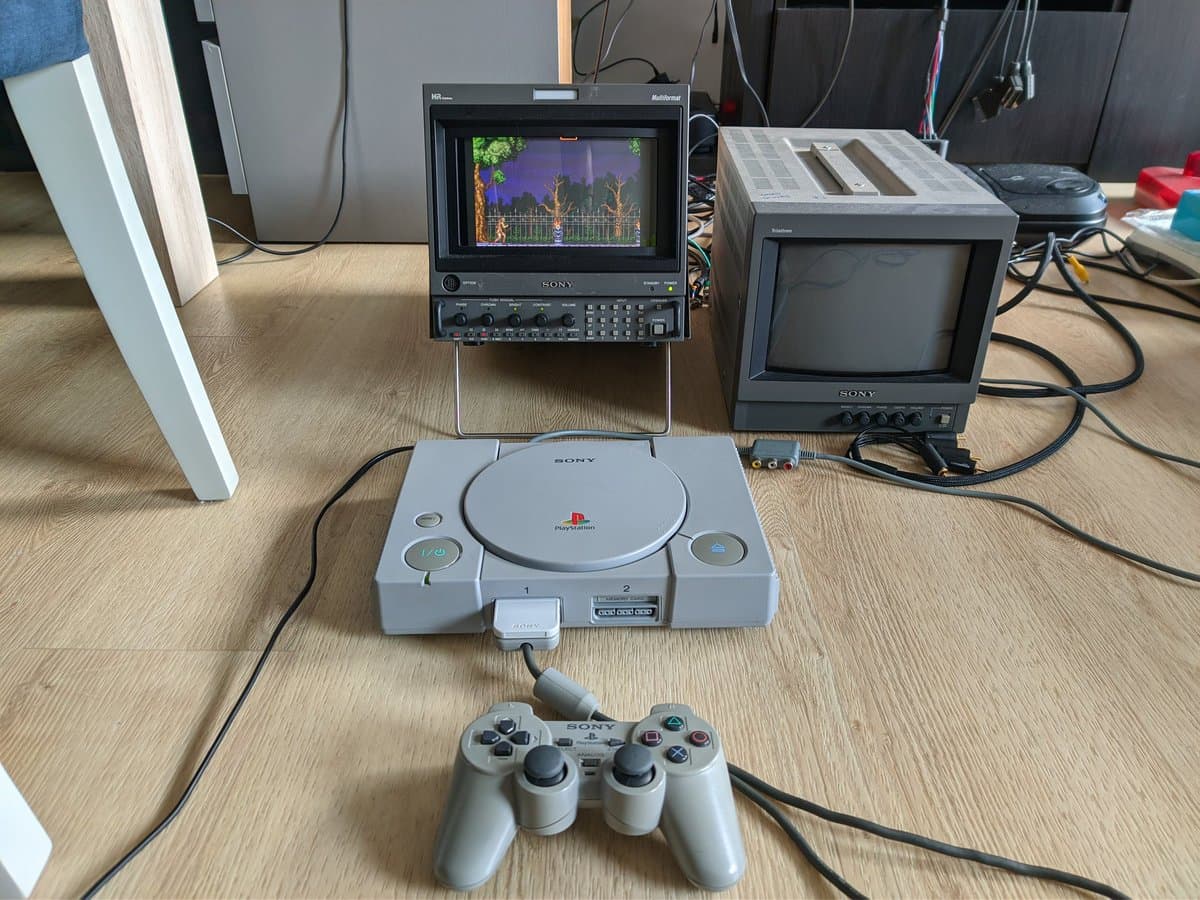 Sony PlayStation PAL console with controller, paired displays showing Castlevania gameplay, power supply recap repair in progress on workbench.