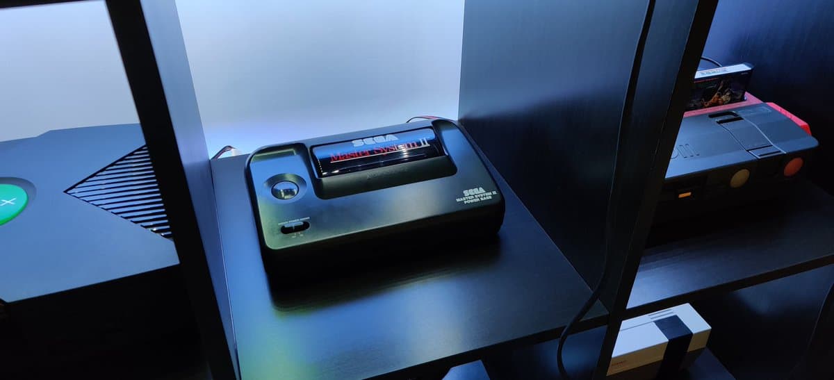 Sega Master System II on display shelf showing RGB mod with new capacitors and voltage regulator installed, ready for testing.