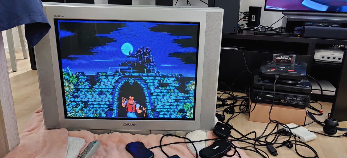 Sega Mega Drive II displaying Castle of Illusion game on CRT monitor with 3BP triple bypass mod installation in progress on workbench.